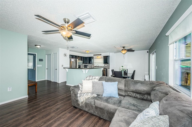 living room with dark hardwood / wood-style flooring, ceiling fan, and a textured ceiling