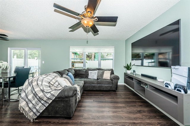 living room featuring dark wood-type flooring, ceiling fan, and a textured ceiling