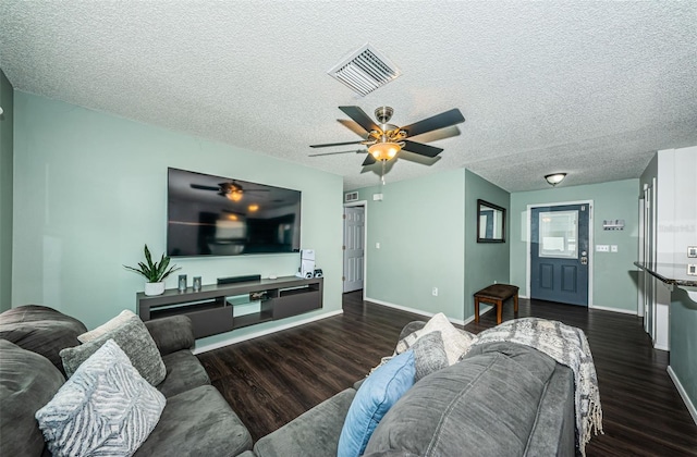 living room featuring dark hardwood / wood-style flooring, ceiling fan, and a textured ceiling