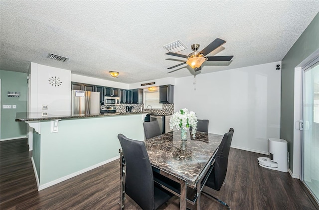 dining room with ceiling fan, dark hardwood / wood-style floors, and a textured ceiling