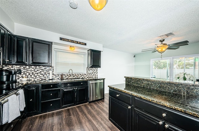 kitchen featuring dishwasher, sink, backsplash, dark hardwood / wood-style flooring, and dark stone counters