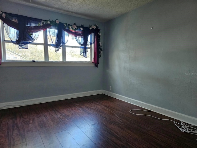 spare room with dark wood-type flooring and a textured ceiling