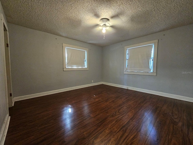 empty room with dark wood-type flooring and a textured ceiling