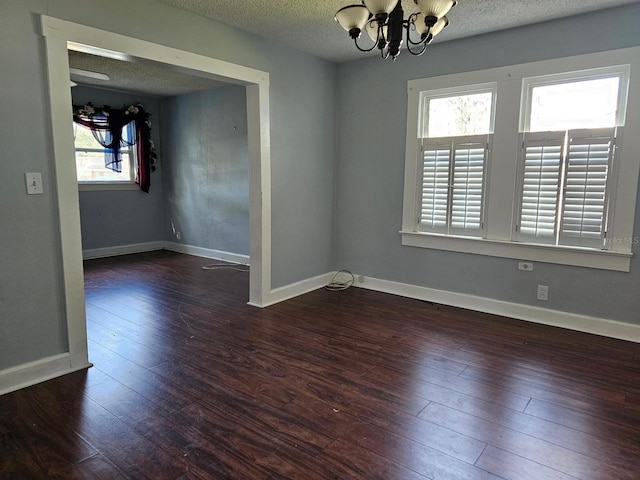 spare room with a notable chandelier, dark hardwood / wood-style floors, and a textured ceiling