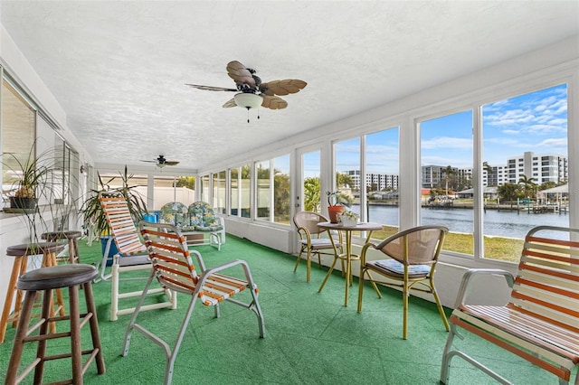 sunroom / solarium with a water view and ceiling fan