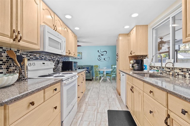 kitchen with sink, tasteful backsplash, light brown cabinets, dark stone countertops, and white appliances