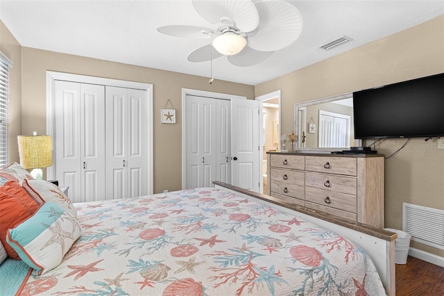 bedroom featuring multiple closets, ceiling fan, and dark wood-type flooring