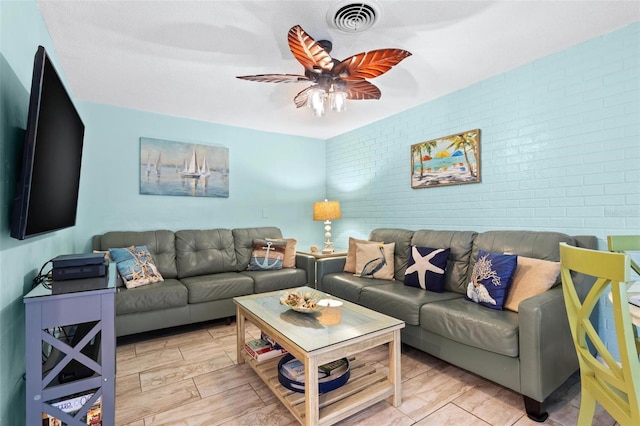 living room featuring ceiling fan and brick wall