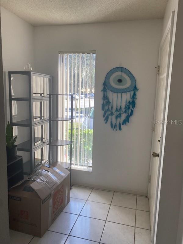 doorway with a textured ceiling and light tile patterned flooring