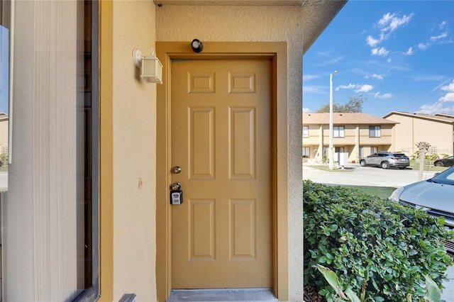 view of exterior entry featuring a residential view and stucco siding