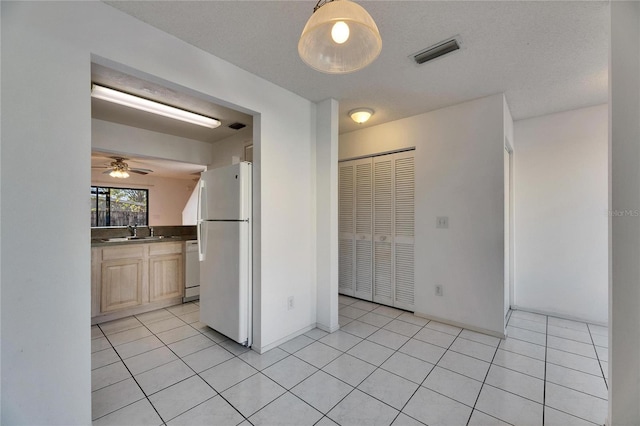 interior space with light tile patterned floors, a closet, visible vents, freestanding refrigerator, and a sink