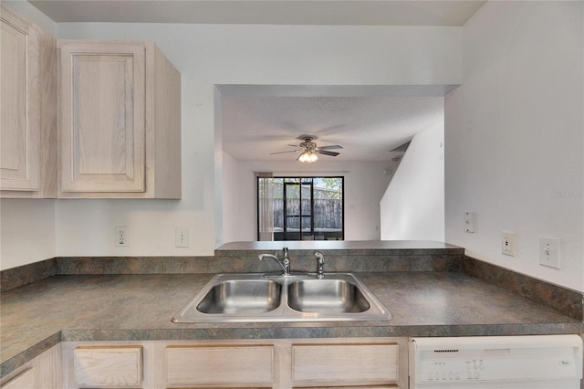 kitchen featuring dark countertops, dishwashing machine, light brown cabinets, and a sink