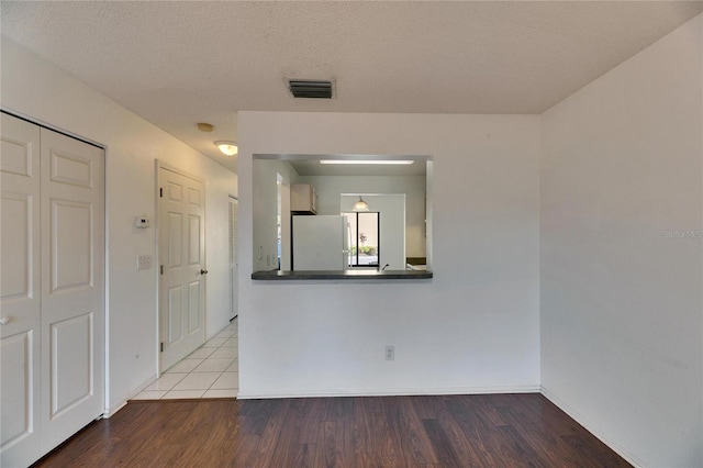 empty room with baseboards, a textured ceiling, visible vents, and wood finished floors