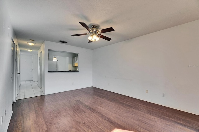 spare room with visible vents, a textured ceiling, a ceiling fan, and wood finished floors