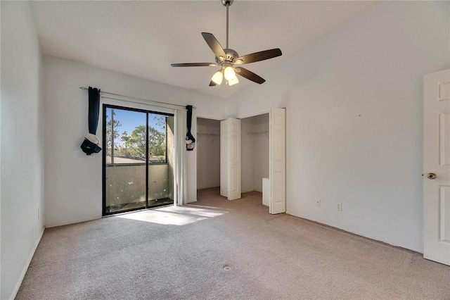 unfurnished bedroom with light carpet, two closets, vaulted ceiling, and a ceiling fan