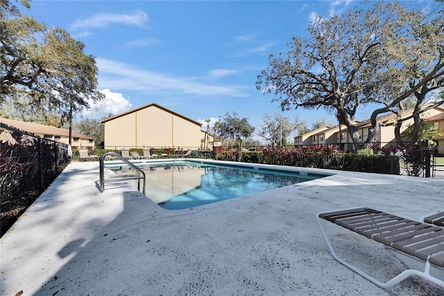 community pool with a patio area and fence