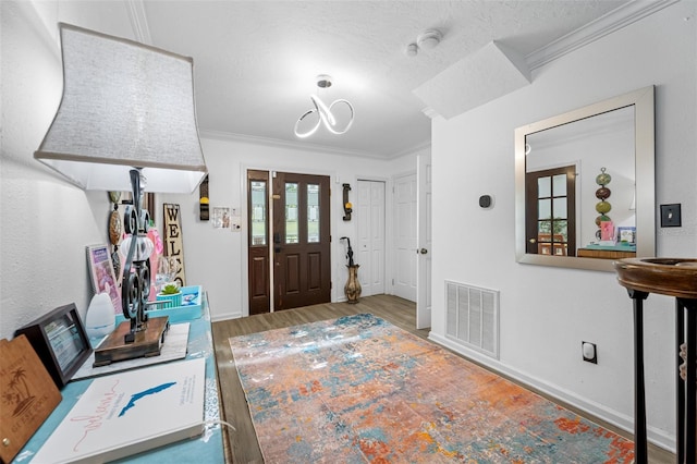 entrance foyer featuring a wealth of natural light, a textured ceiling, and crown molding