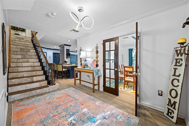 interior space featuring french doors, crown molding, a textured ceiling, and wood-type flooring