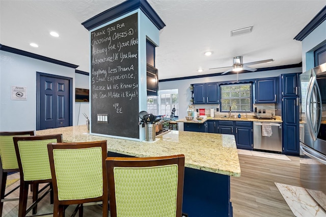 kitchen with blue cabinets, light hardwood / wood-style floors, crown molding, and appliances with stainless steel finishes