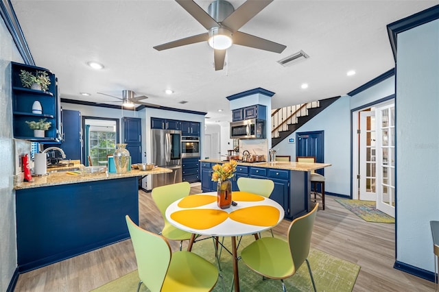 dining room with ceiling fan, sink, ornamental molding, and light wood-type flooring