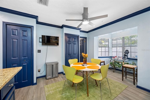 dining space with ceiling fan, light hardwood / wood-style flooring, and crown molding