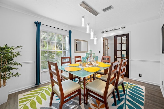 dining area with dark wood-type flooring, a wealth of natural light, and ornamental molding