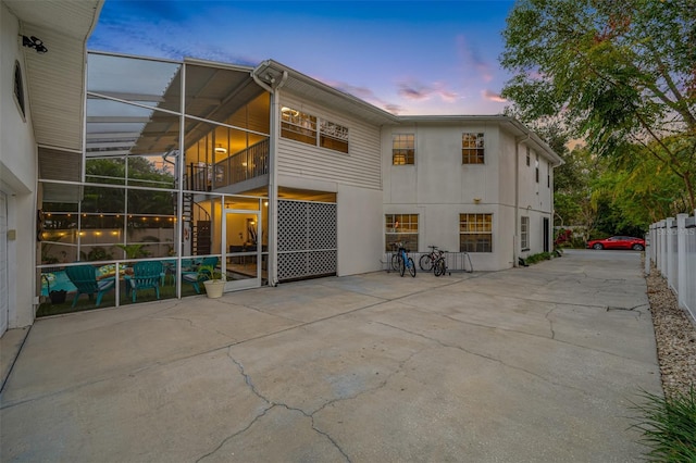 property exterior at dusk featuring glass enclosure