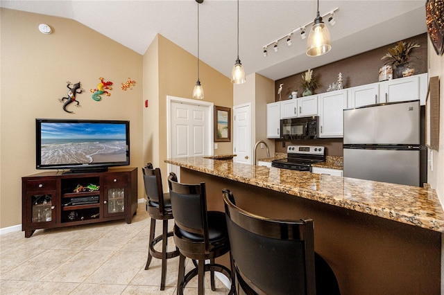 kitchen featuring stone counters, appliances with stainless steel finishes, pendant lighting, white cabinetry, and lofted ceiling