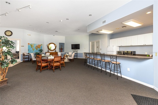 dining space featuring track lighting and dark colored carpet