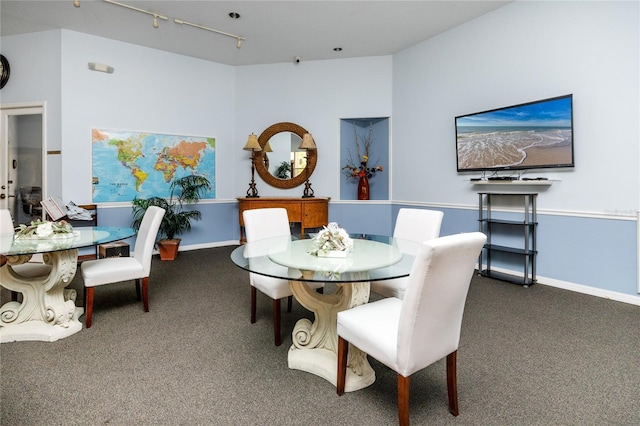 dining room with dark colored carpet and track lighting