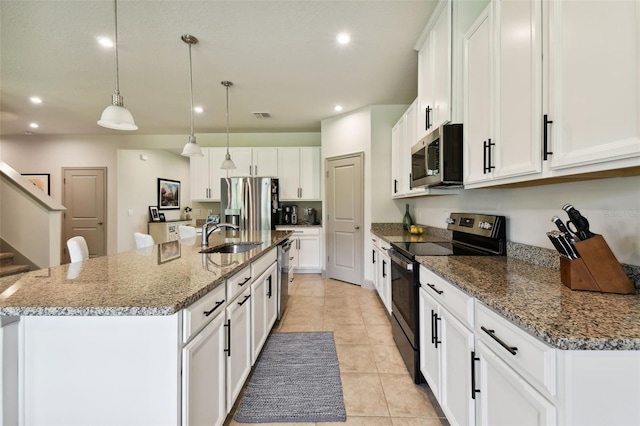 kitchen featuring sink, white cabinetry, decorative light fixtures, appliances with stainless steel finishes, and a kitchen island with sink