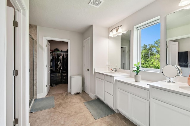 bathroom with vanity, tile patterned flooring, a shower with shower door, and a textured ceiling