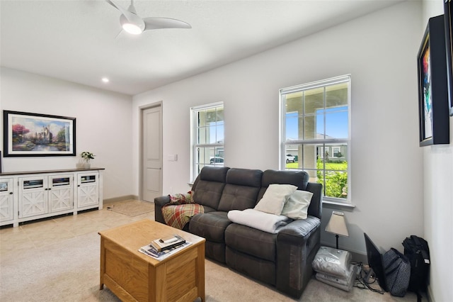 living room with light tile patterned floors, light colored carpet, baseboards, and ceiling fan