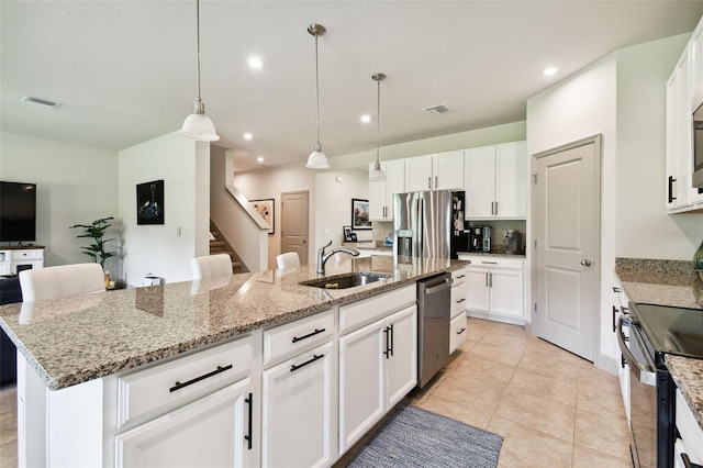 kitchen featuring visible vents, stainless steel appliances, an island with sink, and a sink