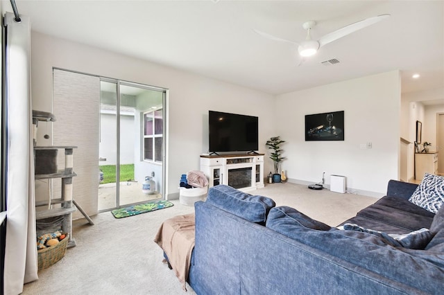 living area with visible vents, baseboards, carpet, and a ceiling fan