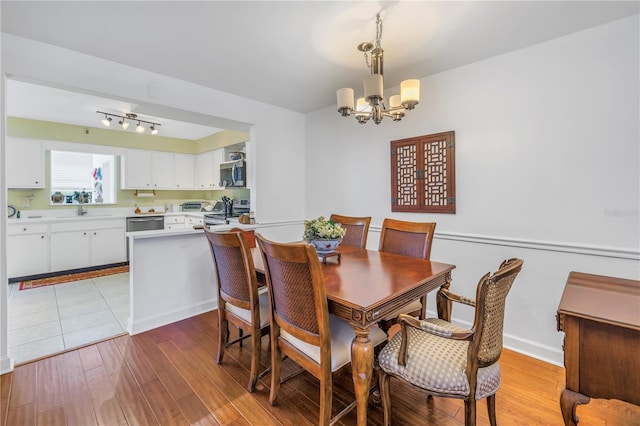 dining room featuring an inviting chandelier, sink, and light hardwood / wood-style floors