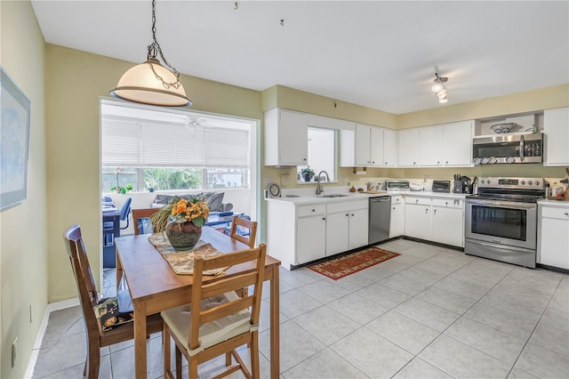 kitchen with sink, white cabinetry, light tile patterned floors, appliances with stainless steel finishes, and pendant lighting