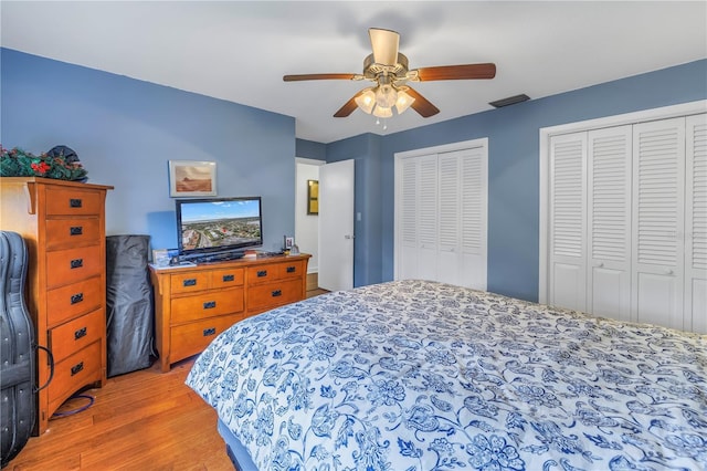 bedroom featuring two closets, light hardwood / wood-style floors, and ceiling fan