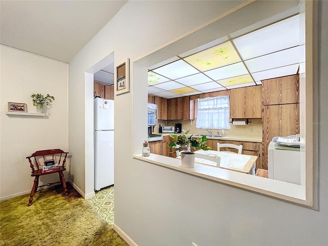 kitchen featuring washer / dryer, sink, kitchen peninsula, white fridge, and light colored carpet