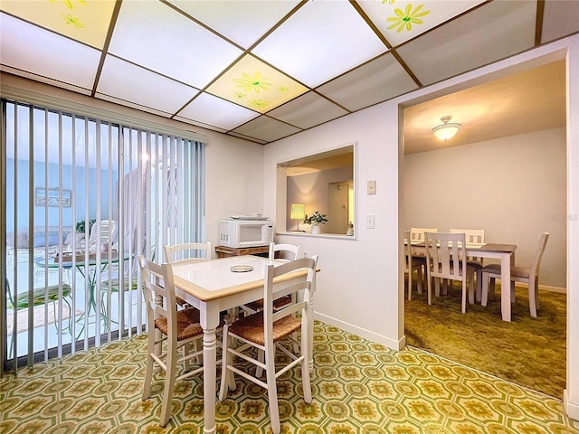 dining space with a water view, a paneled ceiling, and carpet floors