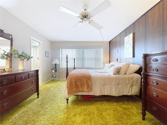 bedroom with ceiling fan, wooden walls, and light carpet