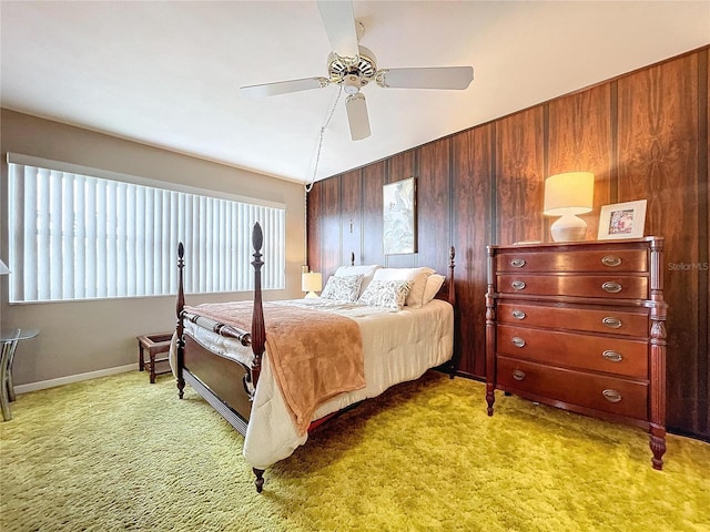 carpeted bedroom featuring ceiling fan and wooden walls