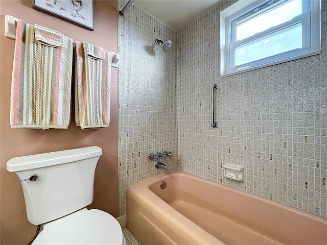 bathroom featuring tiled shower / bath combo and toilet