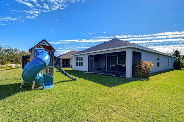 rear view of property with a yard, a playground, and a sunroom