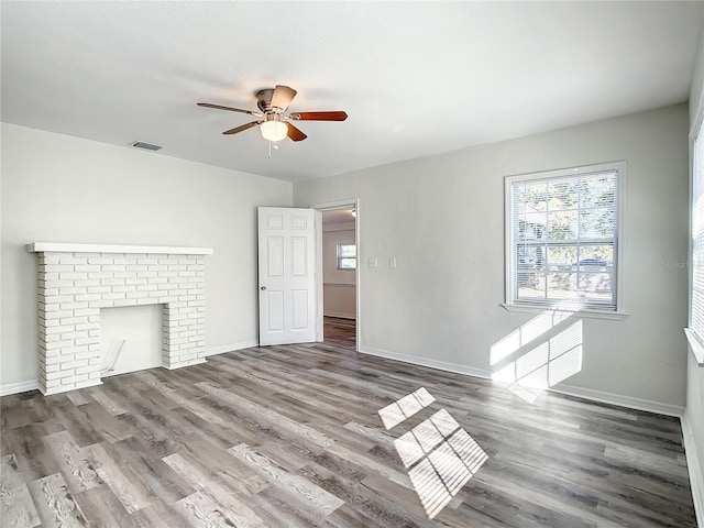 unfurnished living room featuring hardwood / wood-style floors, a brick fireplace, and ceiling fan