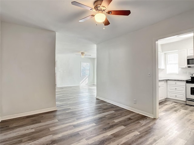 unfurnished room with ceiling fan, wood-type flooring, and a wealth of natural light