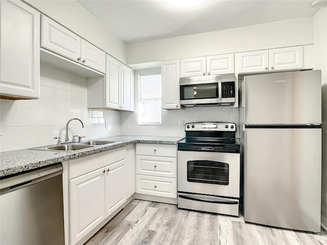 kitchen with sink, light hardwood / wood-style floors, white cabinets, and appliances with stainless steel finishes