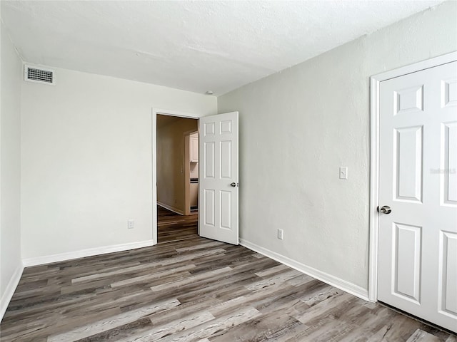 empty room featuring wood-type flooring and a textured ceiling