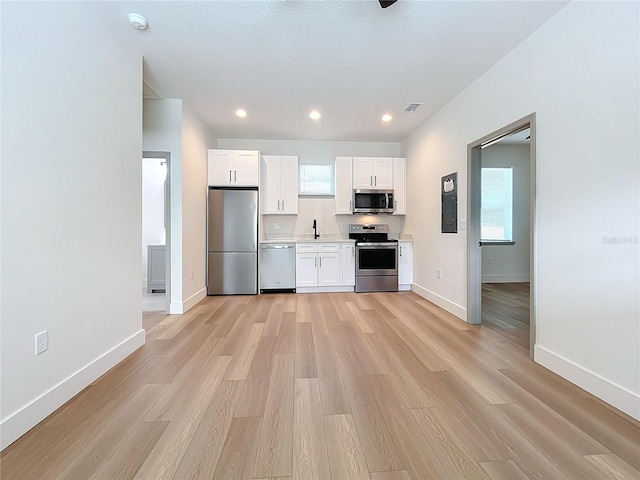 kitchen featuring stainless steel appliances, a wealth of natural light, white cabinets, and light hardwood / wood-style flooring