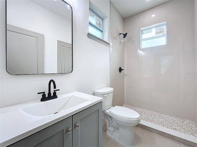 bathroom with vanity, plenty of natural light, toilet, and a tile shower